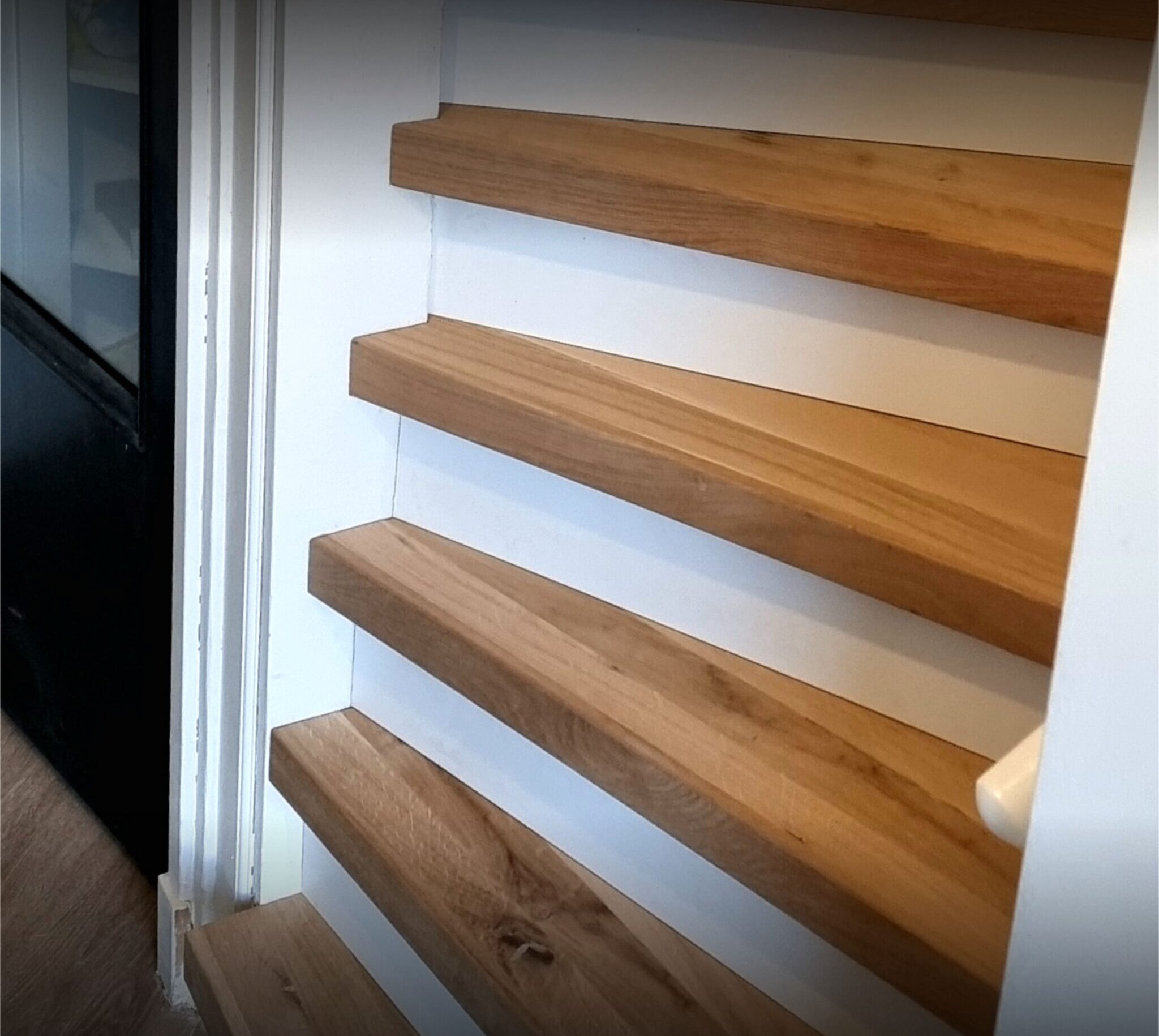 Houten trap in een woning met witte muren